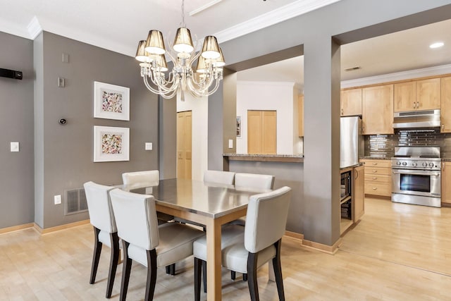 dining area featuring crown molding, an inviting chandelier, and light wood-type flooring