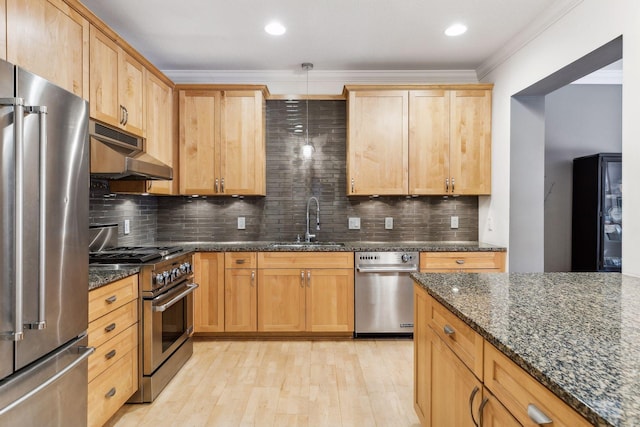 kitchen with high end appliances, sink, ornamental molding, and dark stone counters