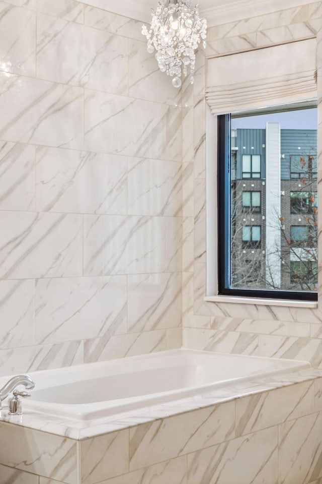 bathroom with tiled tub and a chandelier