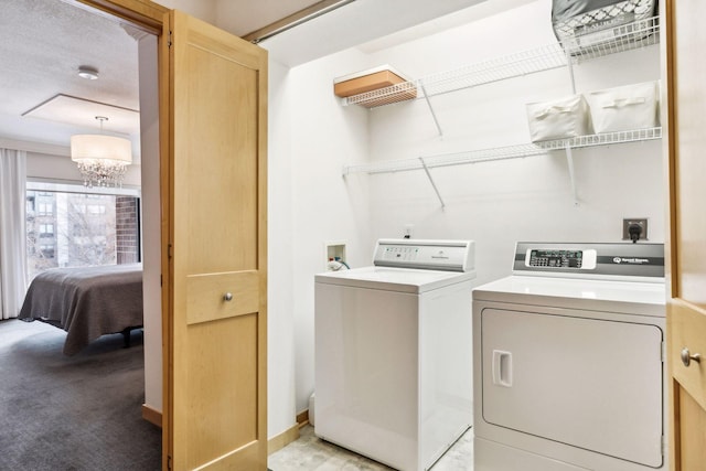 clothes washing area with a chandelier, separate washer and dryer, and light carpet