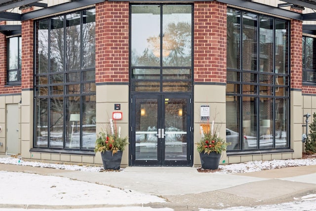 snow covered property entrance featuring french doors