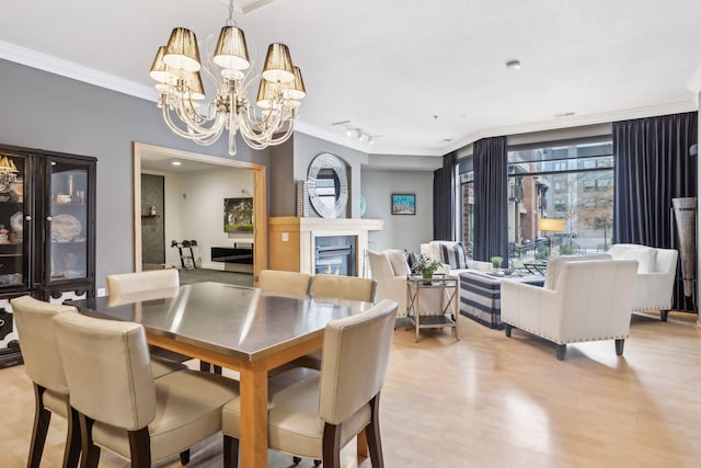 187 Sherman St, Saint Paul, MN 55102 - dining space featuring ornamental molding, a chandelier, a glass covered fireplace, and light wood-style flooring