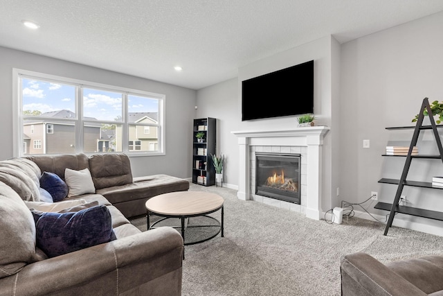 carpeted living room with a textured ceiling, a wealth of natural light, and a tiled fireplace