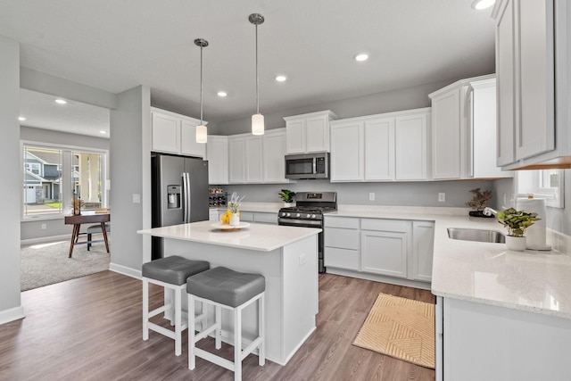 kitchen featuring a kitchen island, white cabinets, light hardwood / wood-style floors, and appliances with stainless steel finishes