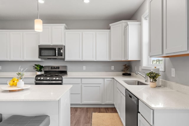 kitchen with light stone counters, stainless steel appliances, sink, decorative light fixtures, and white cabinets