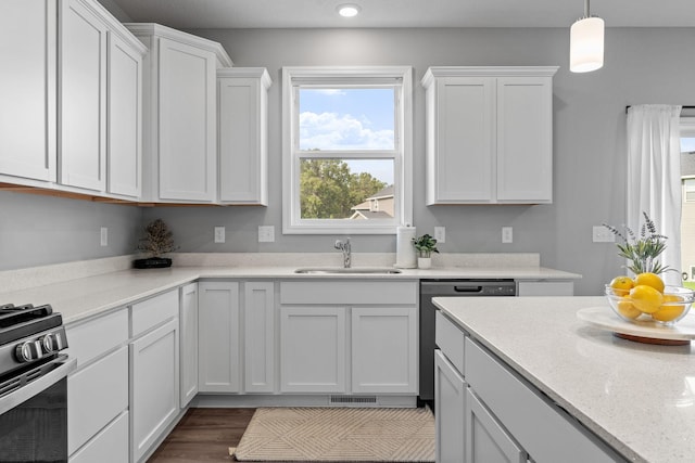 kitchen featuring dishwashing machine, sink, pendant lighting, white cabinets, and stainless steel stove