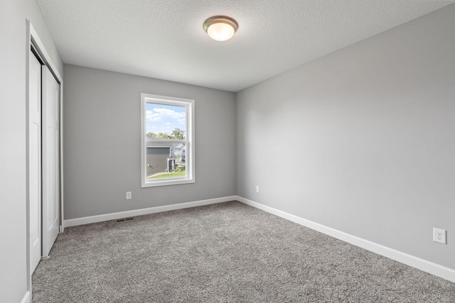 unfurnished bedroom with carpet, a textured ceiling, and a closet