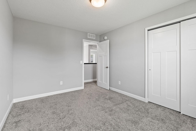 unfurnished bedroom with a closet, light colored carpet, and a textured ceiling