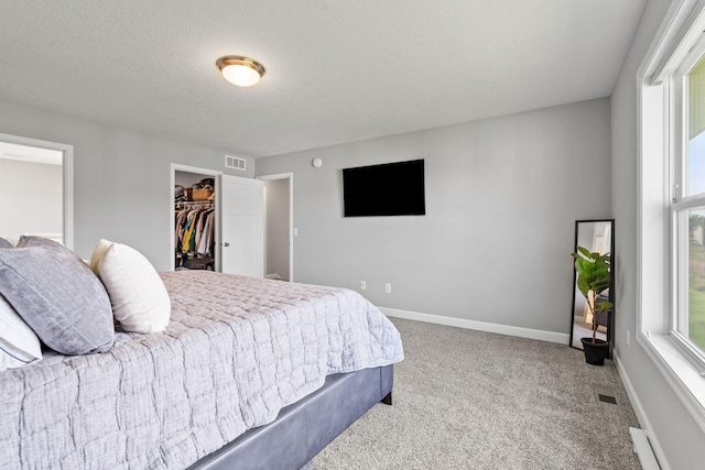 carpeted bedroom with a walk in closet, a closet, and a textured ceiling