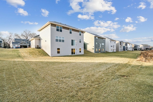 rear view of house featuring a yard and central air condition unit