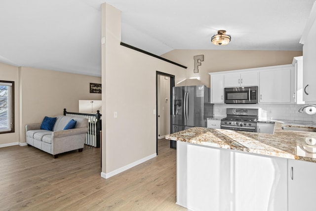 kitchen featuring sink, white cabinets, lofted ceiling, backsplash, and appliances with stainless steel finishes