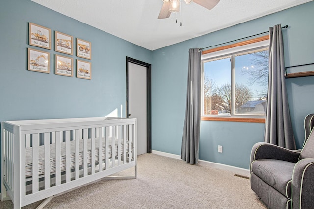 carpeted bedroom with a nursery area and ceiling fan