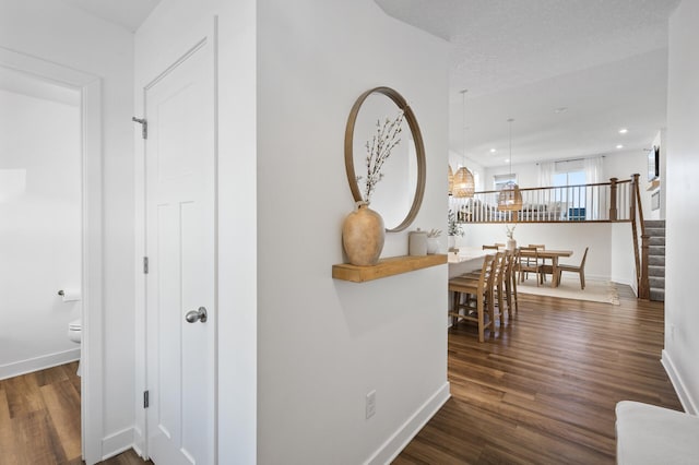 hallway with a textured ceiling and dark wood-type flooring