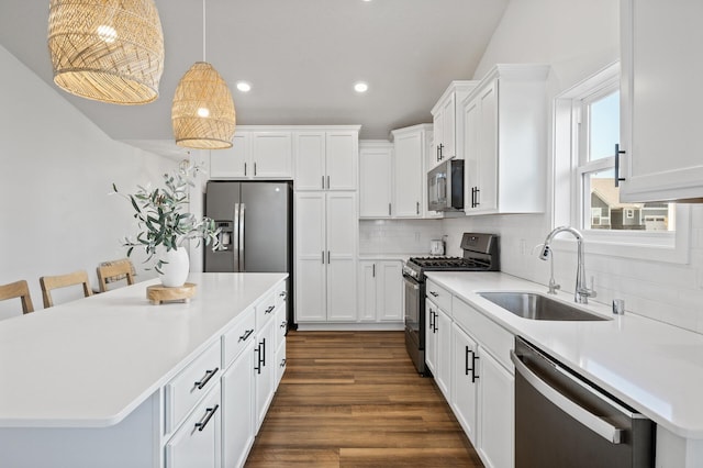 kitchen featuring white cabinetry, sink, pendant lighting, a breakfast bar, and appliances with stainless steel finishes