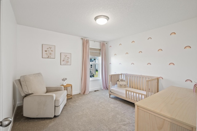 carpeted bedroom with a textured ceiling and a crib