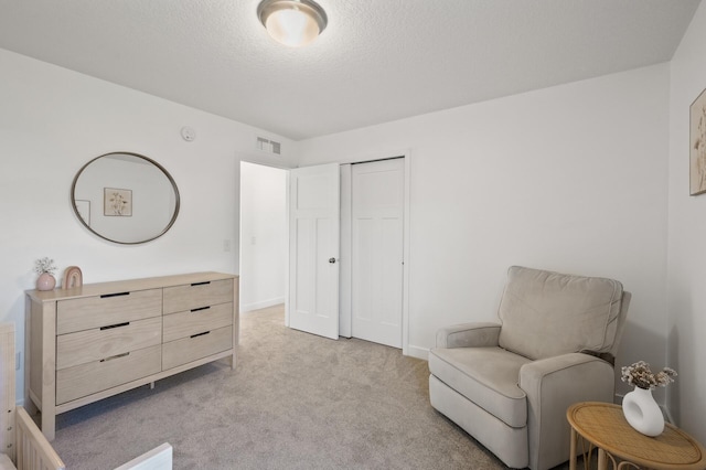 sitting room featuring a textured ceiling and light carpet