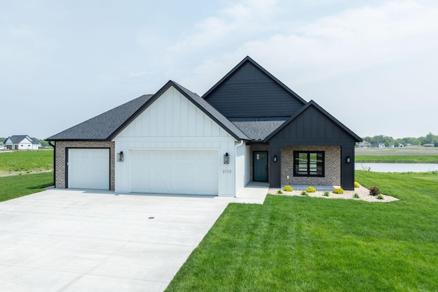 view of front of home featuring a front yard, a water view, and a garage