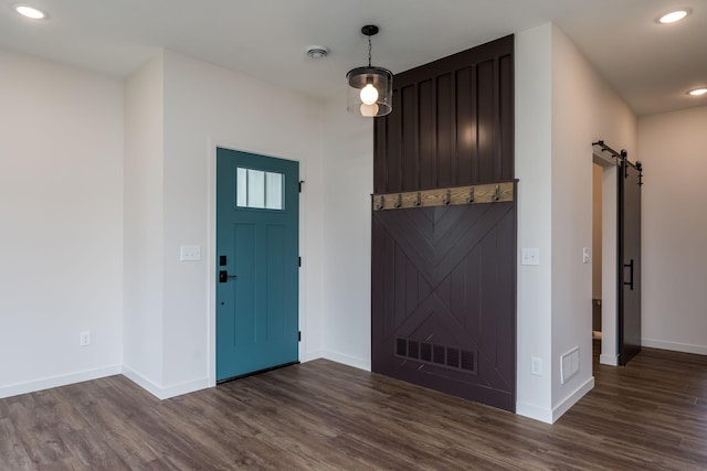 foyer entrance featuring a barn door and dark hardwood / wood-style floors