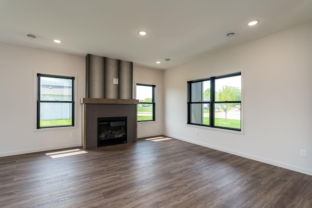 unfurnished living room featuring plenty of natural light, dark hardwood / wood-style flooring, and a fireplace