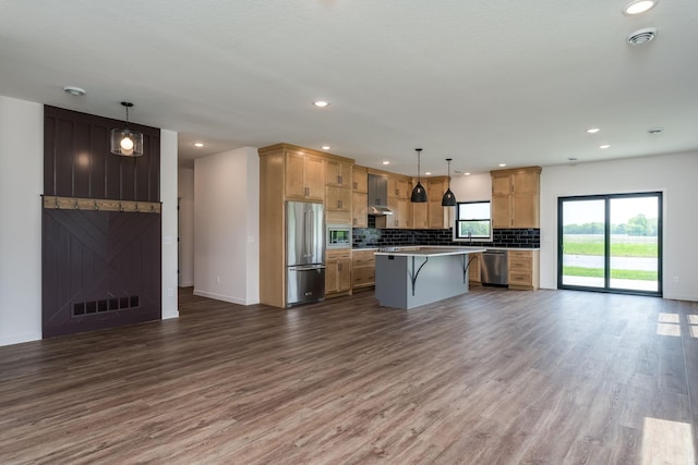 kitchen featuring a center island, hardwood / wood-style flooring, appliances with stainless steel finishes, decorative light fixtures, and a kitchen bar