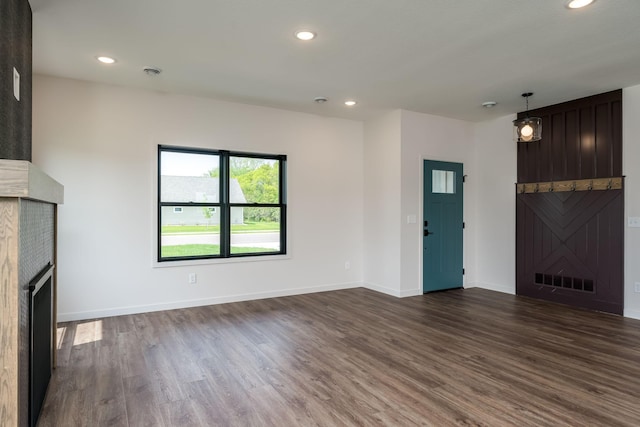 unfurnished living room with a fireplace and dark wood-type flooring