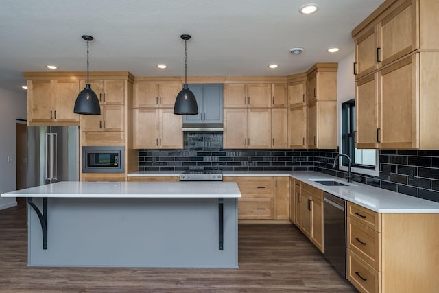 kitchen featuring decorative light fixtures, a center island, sink, and appliances with stainless steel finishes