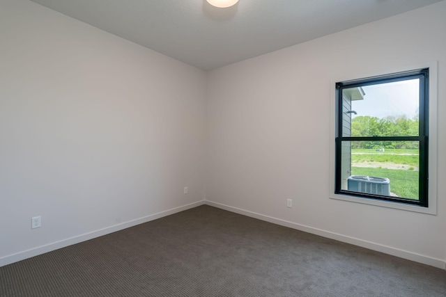 unfurnished room with dark colored carpet and plenty of natural light