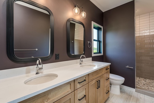 bathroom featuring vanity, toilet, and a tile shower