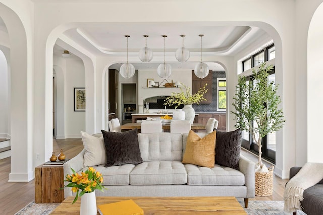 living room with light wood-type flooring, a raised ceiling, and sink