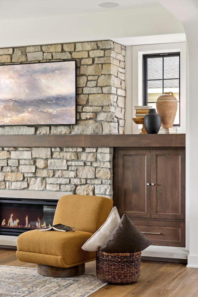 sitting room with hardwood / wood-style floors and a stone fireplace