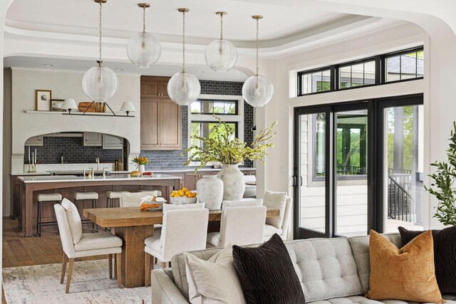 kitchen featuring decorative backsplash, decorative light fixtures, light wood-type flooring, and a tray ceiling