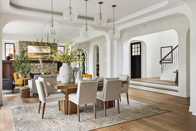 dining area featuring a fireplace, wood-type flooring, and a raised ceiling