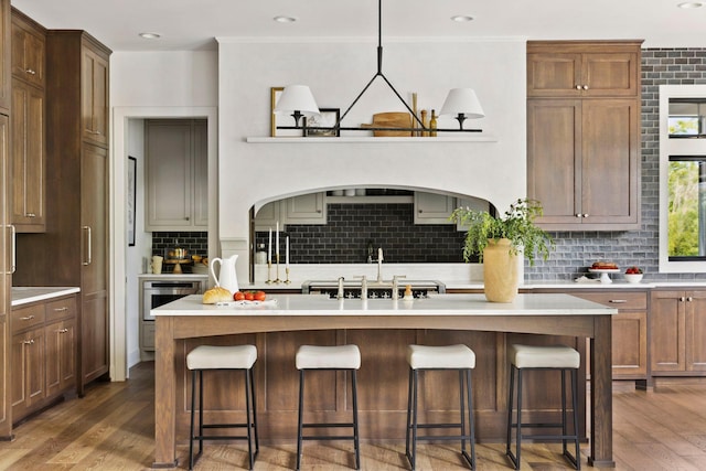 kitchen featuring pendant lighting, decorative backsplash, dark hardwood / wood-style floors, and a kitchen island with sink