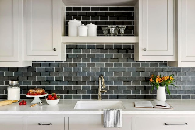 kitchen featuring white cabinetry, decorative backsplash, and sink