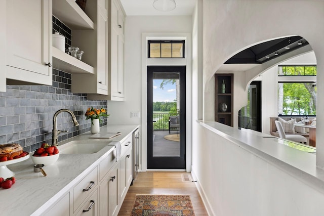 kitchen with white cabinets, light hardwood / wood-style floors, a healthy amount of sunlight, and sink