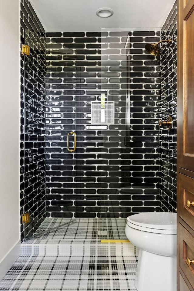 bathroom featuring tile patterned flooring, a tile shower, and toilet