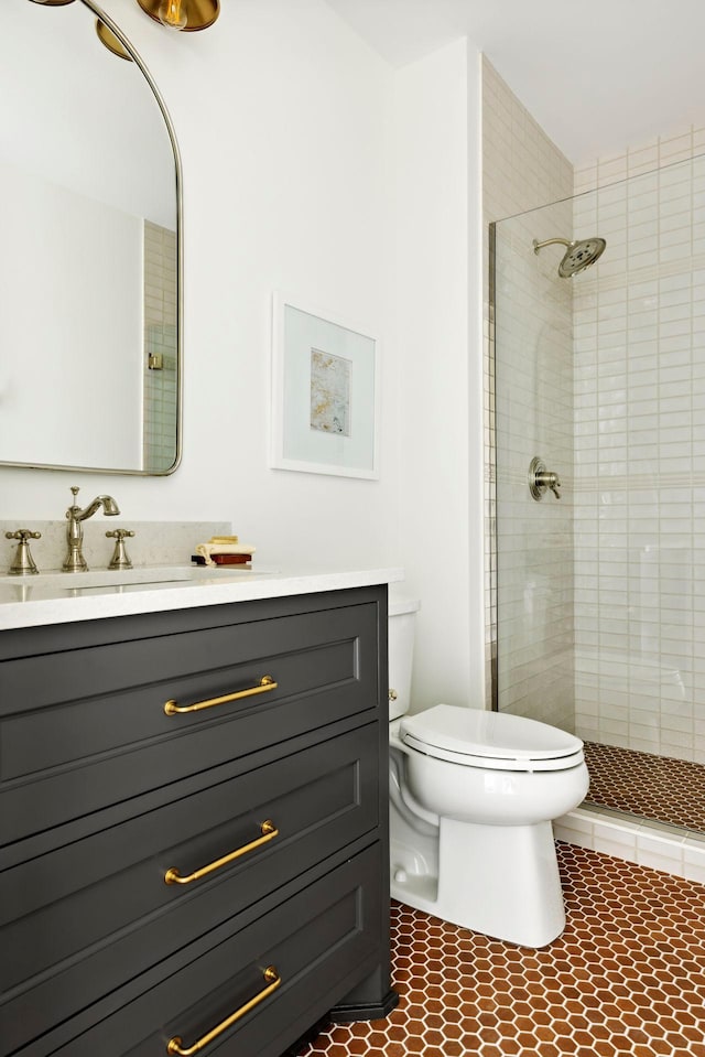 bathroom with tiled shower, tile patterned floors, vanity, and toilet