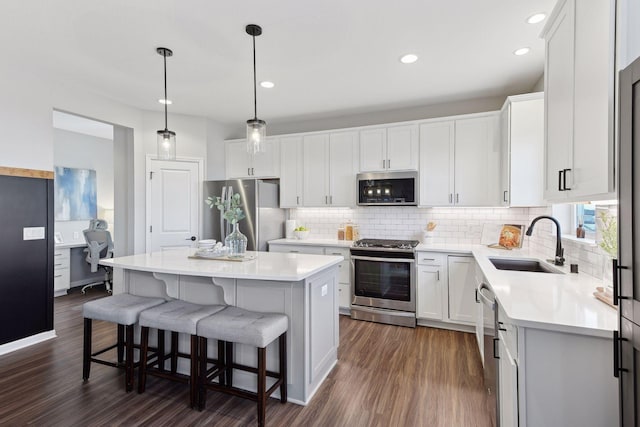 kitchen featuring pendant lighting, sink, appliances with stainless steel finishes, a kitchen island, and white cabinetry