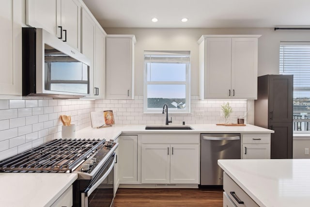 kitchen with decorative backsplash, stainless steel appliances, white cabinetry, and sink