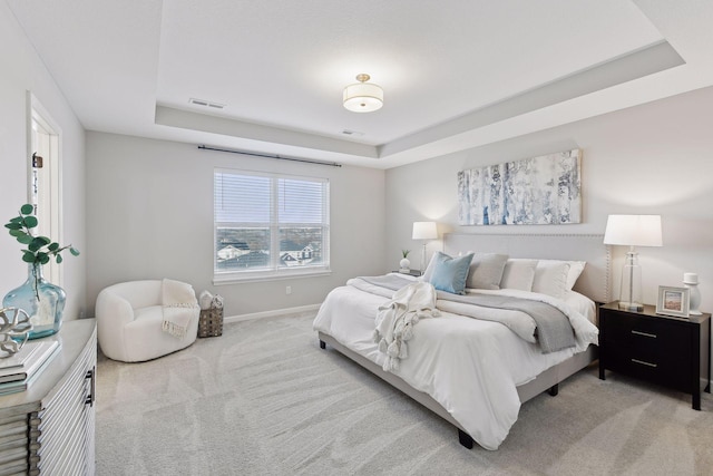 bedroom with a raised ceiling and light colored carpet