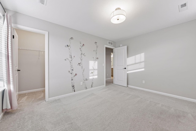 unfurnished bedroom with light colored carpet, a spacious closet, and a closet