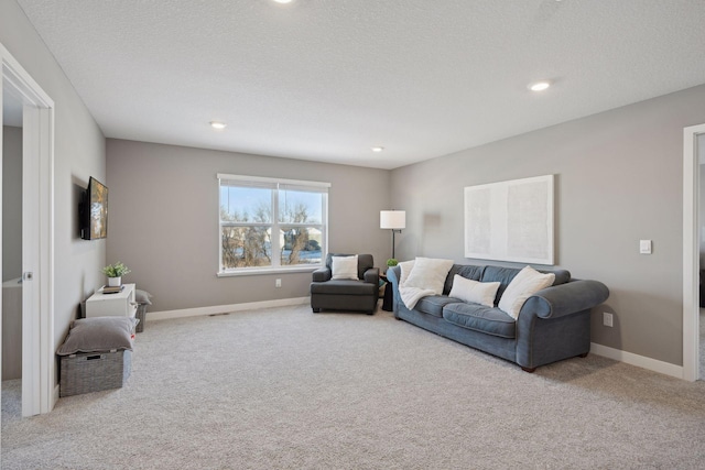 living area featuring baseboards, a textured ceiling, recessed lighting, and light colored carpet