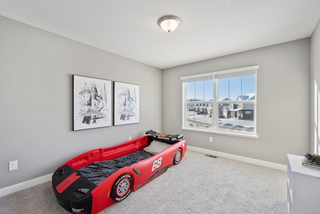 carpeted bedroom with visible vents, a textured ceiling, and baseboards