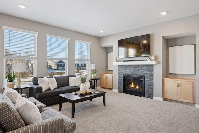 living room featuring recessed lighting, light colored carpet, a stone fireplace, a textured ceiling, and baseboards