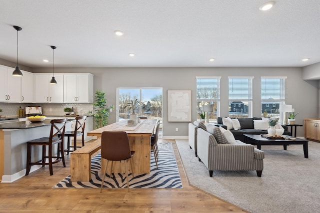 living area with baseboards, recessed lighting, light wood-type flooring, and a healthy amount of sunlight