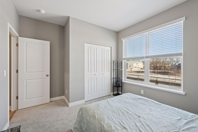 bedroom with light carpet, baseboards, and a closet