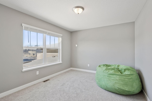 living area featuring carpet, baseboards, visible vents, and a textured ceiling