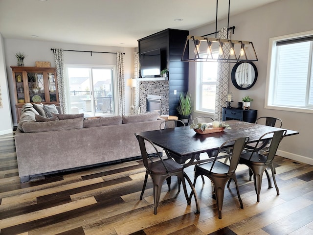 dining space featuring wood-type flooring and a large fireplace