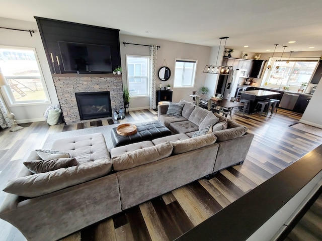 living room featuring an inviting chandelier, a wealth of natural light, a fireplace, and hardwood / wood-style flooring