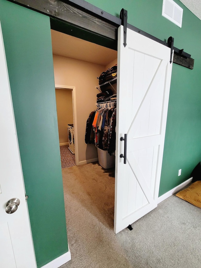 spacious closet with washing machine and clothes dryer, carpet, and a barn door